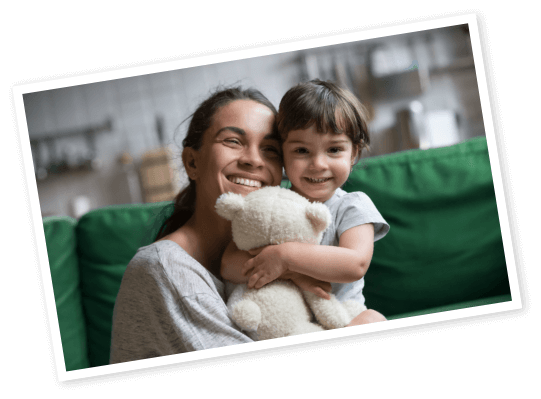 photo of woman hugging a young child who is holding a stuffed animal