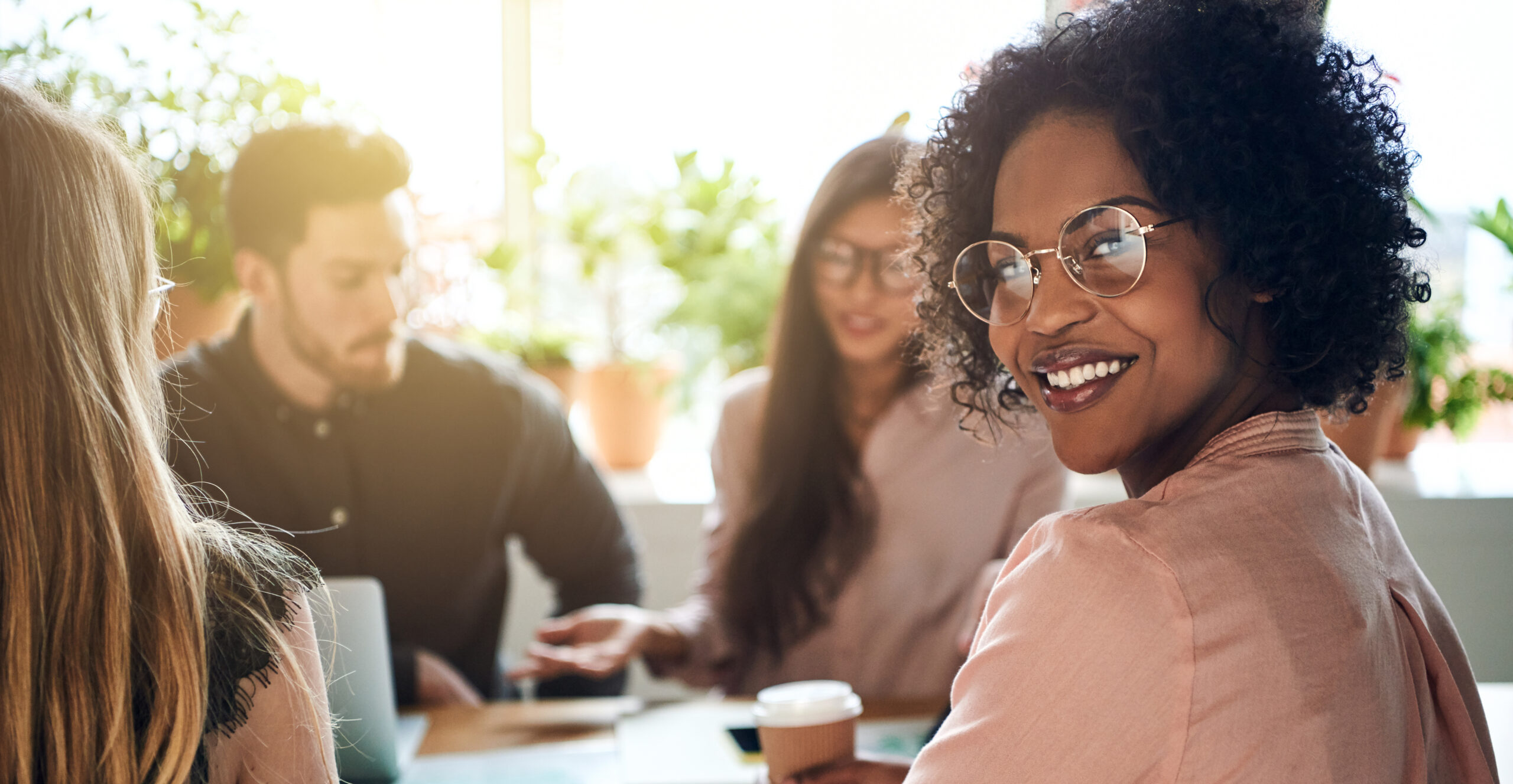 Smiling African businesswoman sitting with diverse coworkers in a boardroom